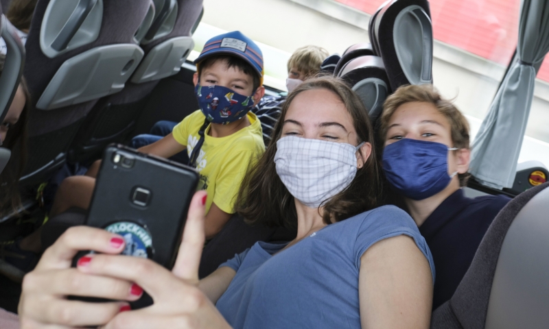 Betreuerin und zwei Lagerlinge machen mit Smartphone bei der Hinfahrt im Bus ein Selfie